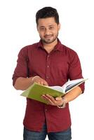 Young happy man holding and posing with the book on white background. photo