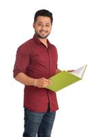 Young happy man holding and posing with the book on white background. photo