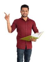 Young happy man holding and posing with the book on white background. photo