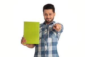 Young happy man holding and posing with the book on white background. photo