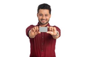 Young smiling handsome man posing with a credit or debit card on white background. photo