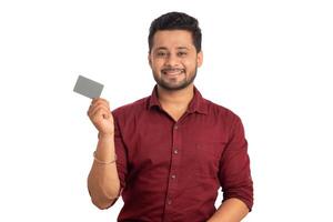 Young smiling handsome man posing with a credit or debit card on white background. photo