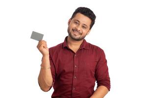 Young smiling handsome man posing with a credit or debit card on white background. photo