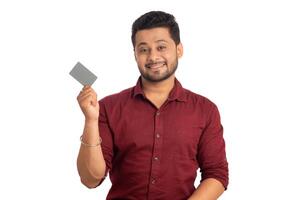 Young smiling handsome man posing with a credit or debit card on white background. photo