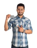 Young smiling handsome man posing with a credit or debit card on white background. photo