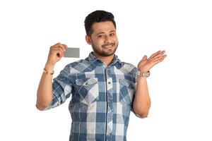 Young smiling handsome man posing with a credit or debit card on white background. photo