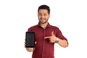 Young handsome man, businessman showing a blank screen of a smartphone or mobile or tablet phone on white background photo