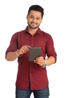 Young handsome man holding and using smartphone or mobile or tablet phone on a white background photo