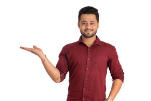 Portrait of a successful cheerful young man holding and presenting something on hand with a happy smiling face. photo