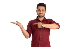Portrait of a successful cheerful young man holding and presenting something on hand with a happy smiling face. photo