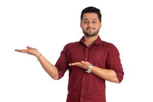 Portrait of a successful cheerful young man holding and presenting something on hand with a happy smiling face. photo