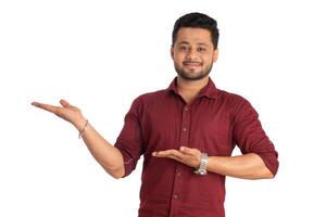 Portrait of a successful cheerful young man holding and presenting something on hand with a happy smiling face. photo