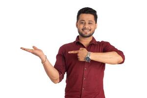 Portrait of a successful cheerful young man holding and presenting something on hand with a happy smiling face. photo