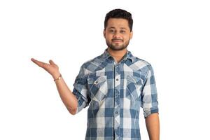 Portrait of a successful cheerful young man holding and presenting something on hand with a happy smiling face. photo