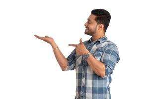 Portrait of a successful cheerful young man holding and presenting something on hand with a happy smiling face. photo