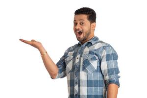 Portrait of a successful cheerful young man holding and presenting something on hand with a happy smiling face. photo