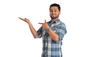 Portrait of a successful cheerful young man holding and presenting something on hand with a happy smiling face. photo