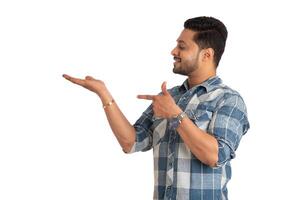 Portrait of a successful cheerful young man holding and presenting something on hand with a happy smiling face. photo