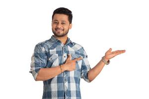 Portrait of a successful cheerful young man holding and presenting something on hand with a happy smiling face. photo
