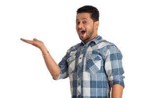 Portrait of a successful cheerful young man holding and presenting something on hand with a happy smiling face. photo