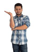 Portrait of a successful cheerful young man holding and presenting something on hand with a happy smiling face. photo