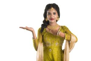 Portrait of cheerful Indian traditional young woman presenting something, showing copy space on her palm on a white background photo