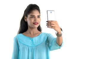 Young Indian girl using a mobile phone or smartphone isolated on a white background photo