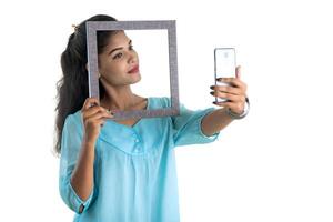 Young Indian girl using a mobile phone or smartphone with photo frame on a white background