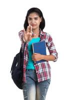 young Indian woman with backpack standing and holding notebooks, posing on a white background. photo