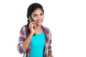 Young Indian girl using a mobile phone or smartphone isolated on a white background photo