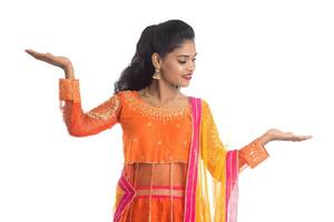 Portrait of cheerful Indian traditional young woman presenting something on hand, showing copy space on her palm on a white background photo