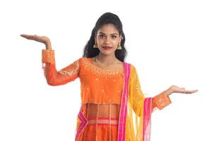 Portrait of cheerful Indian traditional young woman presenting something on hand, showing copy space on her palm on a white background photo