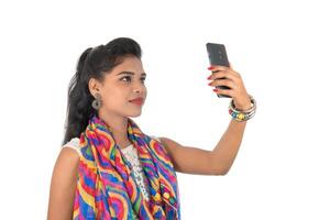 Young Indian girl using a mobile phone or smartphone isolated on a white background photo