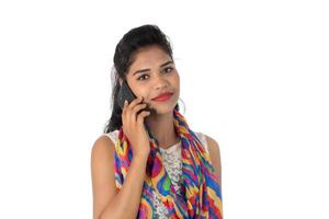 Young Indian girl using a mobile phone or smartphone isolated on a white background photo