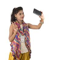 Young Indian girl using a mobile phone or smartphone isolated on a white background photo