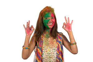 Portrait of a happy young girl with a colorful face on Holi color festival on white background photo
