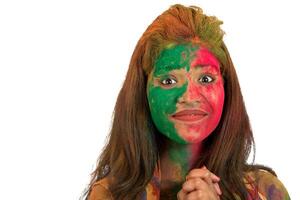 Portrait of a happy young girl with a colorful face on Holi color festival on white background photo