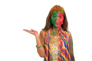 Young girl with a colorful face holding and presenting something on the hand with a happy smiling on occasion of Holi festival. Festival and technology concept. photo
