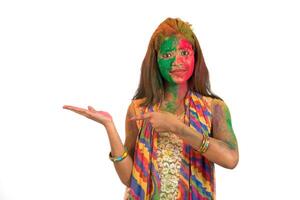 Young girl with a colorful face holding and presenting something on the hand with a happy smiling on occasion of Holi festival. Festival and technology concept. photo