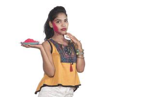 Beautiful young girl holding powdered color on a plate and enjoying colors on the occasion of the Holi festival. photo