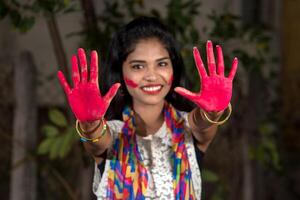 Young girl showing colorful palm and celebrating Holi with color splash photo