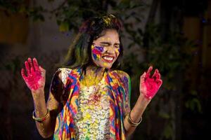 Young girl showing colorful palm and celebrating Holi with color splash photo