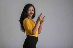 Portrait of a successful cheerful young girl holding and presenting something on hand with a happy smiling face. photo