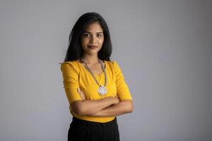 Portrait of a beautiful, smiling, emotional young woman posing with hands-folded on gray background. photo