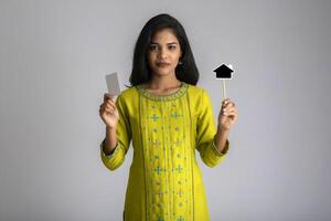 Young smiling beautiful girl showing a credit card or blank card with a black board on grey background. photo