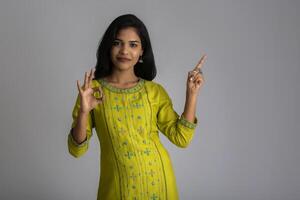 Portrait of a successful cheerful young girl holding and presenting something on hand with a happy smiling face. photo