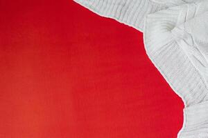 White knitted plaid on a red background in the corner. Flat lay. Copy Space photo