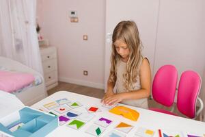 Lifestyle of a smart girl playing a logic game at home. The concept of board games for children, a candid series with real people in a modern interior photo