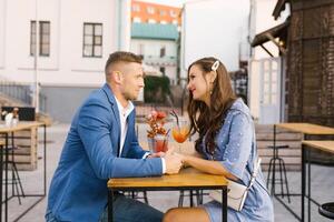 Beautiful couple in love is sitting at a table in an outdoor cafe on a date photo