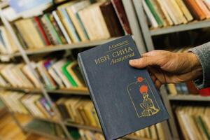 Kagan, Uzbekistan. December 2022. The book of Ibn Sina Avicenna in the hands of a man in the library photo